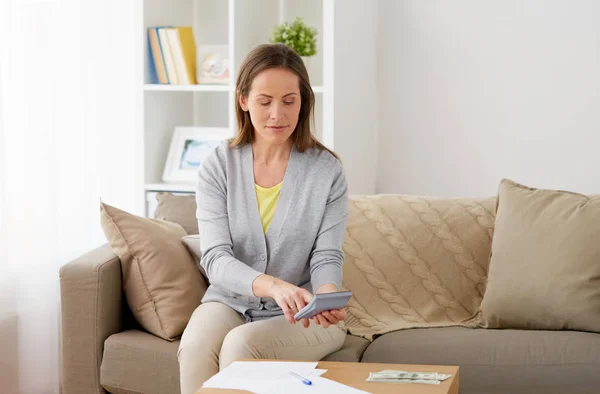 Vrouw met geld, papieren en rekenmachine thuis — Stockfoto