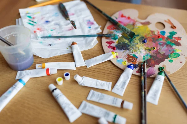 Palette, brushes and paint tubes on table — Stock Photo, Image