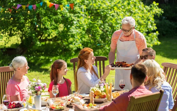 Família feliz ter jantar ou festa no jardim de verão — Fotografia de Stock