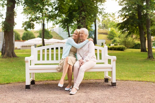 Figlia con mamma anziana che si abbraccia sulla panchina del parco — Foto Stock