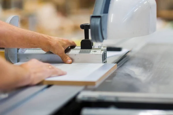 Carpenter with panel saw and fibreboard at factory — Stock Photo, Image