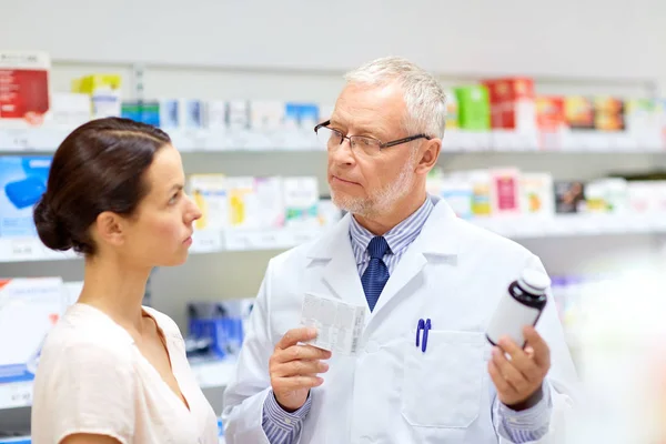 Apothicaire et femme avec des médicaments à la pharmacie — Photo