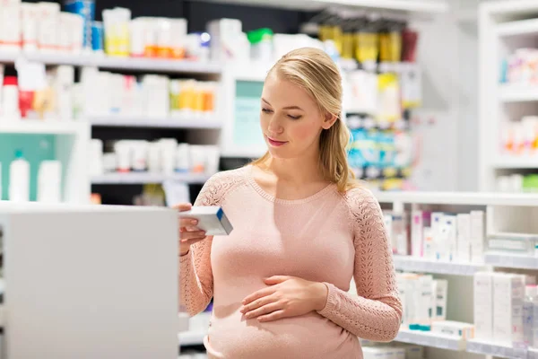 Gelukkig zwangere vrouw met medicatie bij apotheek — Stockfoto