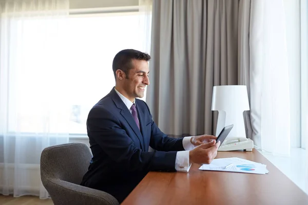 Homem de negócios com tablet pc trabalhando no quarto de hotel — Fotografia de Stock