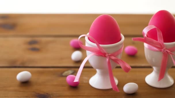 Пасхальные яйца в держателях и конфеты на столе — стоковое видео