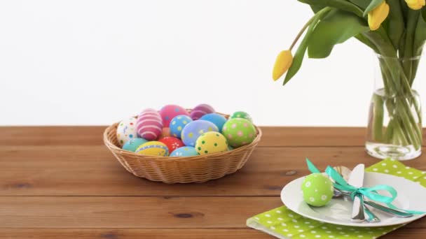 Пасхальные яйца в корзине и цветы на обслуживаемом столе — стоковое видео