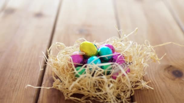 Chocolate easter eggs in straw nest on table — Stock Video