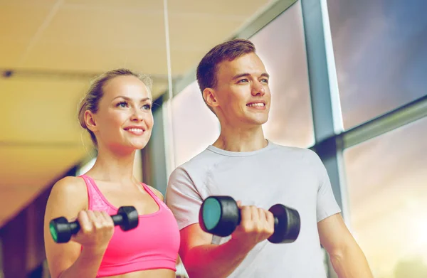 Spor salonunda kişisel antrenörüyle gülümseyen genç bir kadın. — Stok fotoğraf