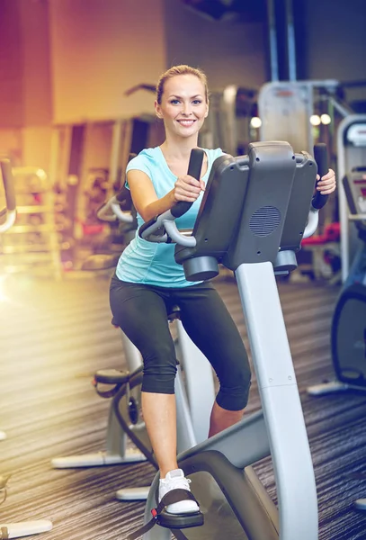 Mulher sorridente exercitando-se em bicicleta de exercício no ginásio — Fotografia de Stock