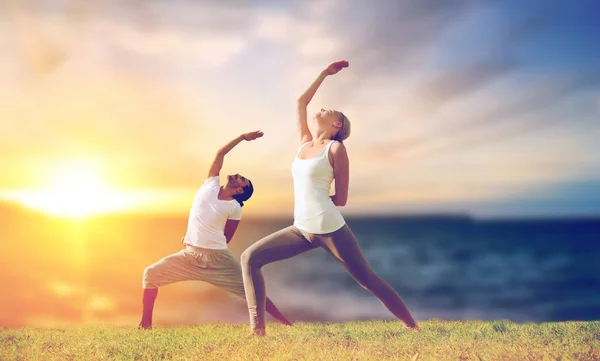 Pareja haciendo yoga guerrero pose al aire libre —  Fotos de Stock