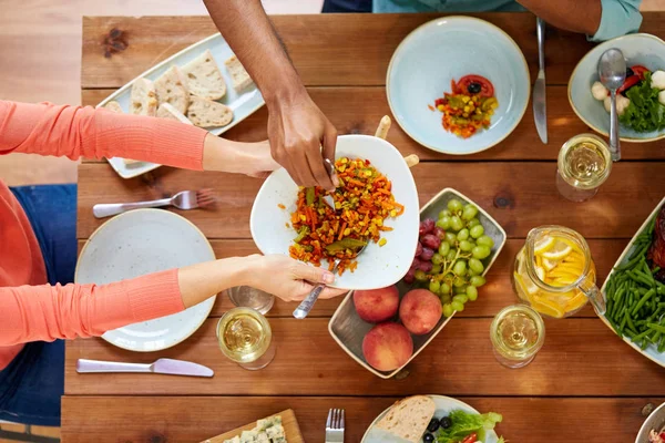 Personas comiendo ensalada en la mesa con comida — Foto de Stock