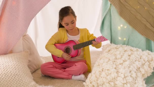 Flicka med leksak gitarrspel i barn tält hemma — Stockvideo