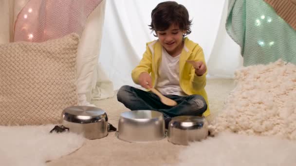 Niño con ollas tocando música en tienda de campaña para niños en casa — Vídeo de stock