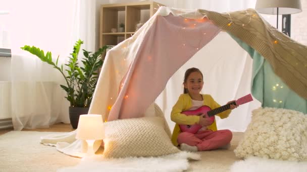Mädchen mit Spielzeuggitarre spielt zu Hause im Kinderzelt — Stockvideo