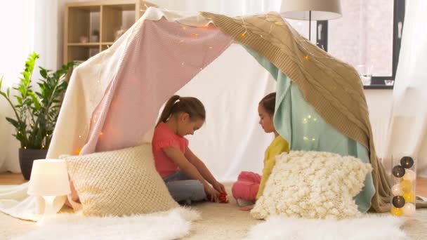 Счастливые девочки в детской палатке играют чаепитие дома — стоковое видео