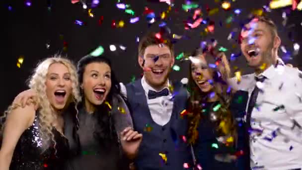 Gelukkige vrienden op feest onder confetti over zwart — Stockvideo