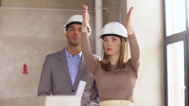 Architecten met blauwdruk en helmen op kantoor — Stockvideo