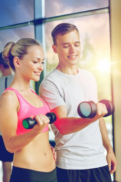 Lächelnde junge Frau mit Personal Trainer im Fitnessstudio — Stockfoto