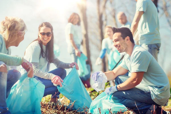 Relawan dengan kantong sampah membersihkan area taman — Stok Foto