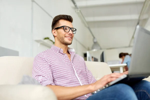 Smiling man with laptop working at office — Stock Photo, Image