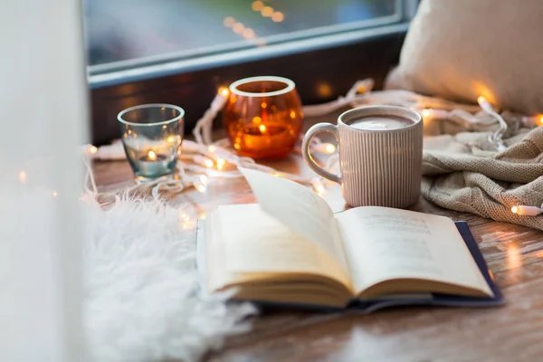 Könyv és kávé vagy forró cchocolate a ablakpárkányon — Stock Fotó