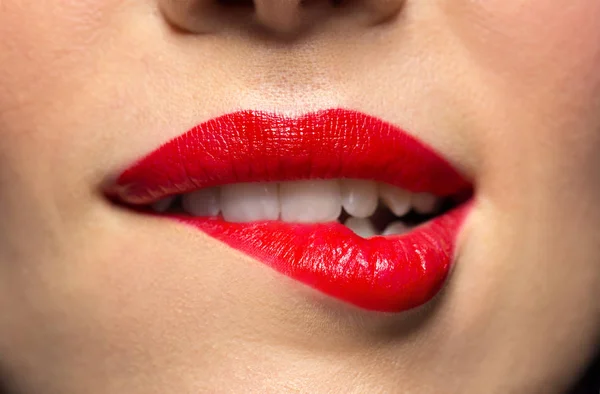 Close up van vrouw met rode lippenstift lip bijten — Stockfoto