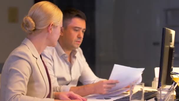 Equipo de negocios con papeles trabajando hasta tarde en la oficina — Vídeo de stock