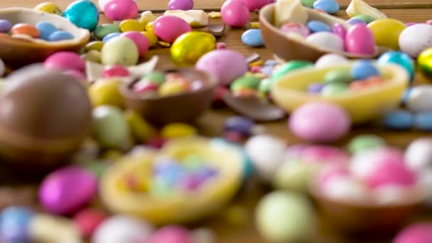 Huevos de pascua de chocolate y dejar caer caramelos en la mesa — Vídeos de Stock