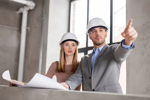 Architekten mit Blaupause und Helmen im Büro — Stockfoto