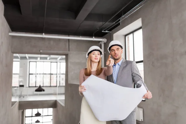 Architects with blueprint and helmets at office — Stock Photo, Image