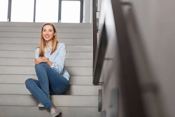 Heureuse souriante femme ou étudiant assis sur les escaliers — Photo