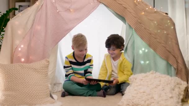 Niños pequeños con tablet pc en tienda de campaña para niños en casa — Vídeos de Stock