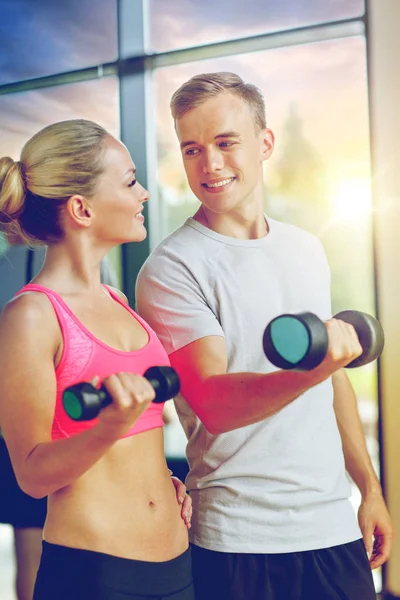 Sonriente joven con entrenador personal en el gimnasio — Foto de Stock