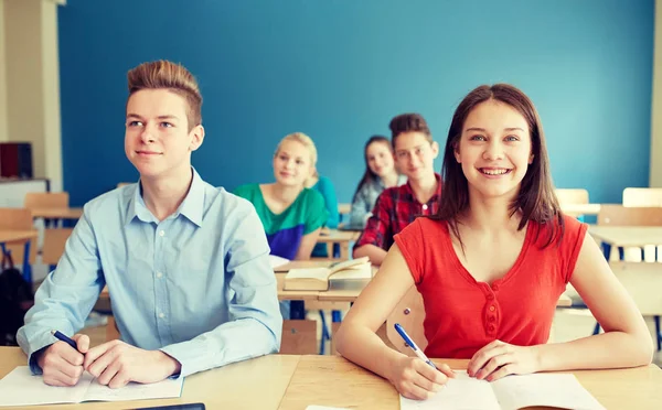 Estudiantes felices con cuadernos en la escuela —  Fotos de Stock