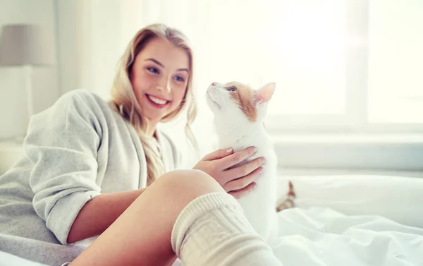 Jovem feliz com gato na cama em casa — Fotografia de Stock