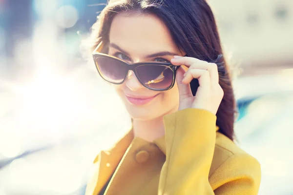 Lachende jonge vrouw met een zonnebril in de stad — Stockfoto