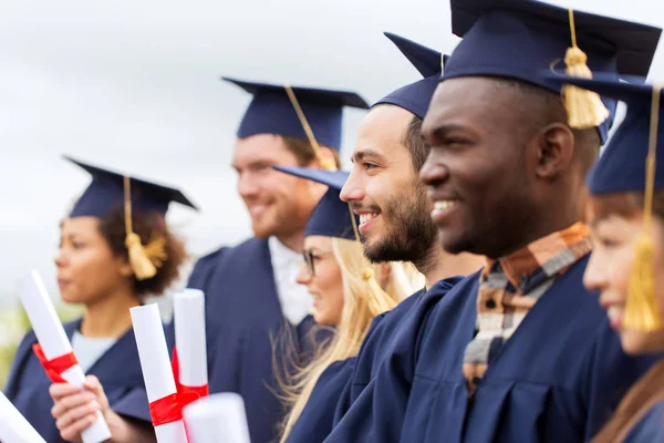 Zadowoleni studenci w moździerzy z dyplomami — Zdjęcie stockowe