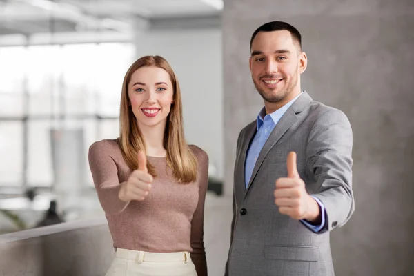 Business woman and businessman showing thumbs up — стоковое фото