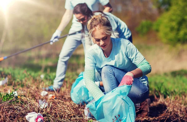 Relawan dengan kantong sampah membersihkan area taman — Stok Foto