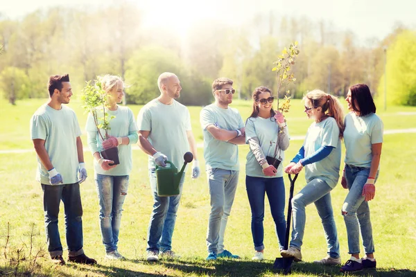 Grupo de voluntarios con árboles y rastrillo en el parque — Foto de Stock