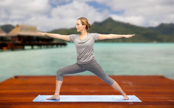 Mujer haciendo yoga guerrero pose en estera al aire libre —  Fotos de Stock