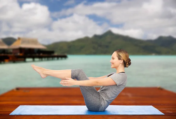 Mujer haciendo yoga media embarcación pose en la estera al aire libre — Foto de Stock