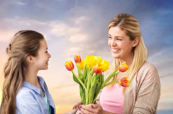 Gelukkige dochter geven van bloemen naar de moeder over hemel — Stockfoto