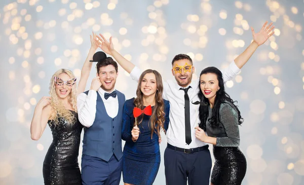 Glückliche Freunde mit Party-Requisiten posieren über Lichtern — Stockfoto