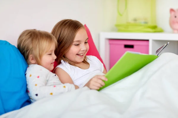 Meninas ou irmãs lendo livro na cama — Fotografia de Stock
