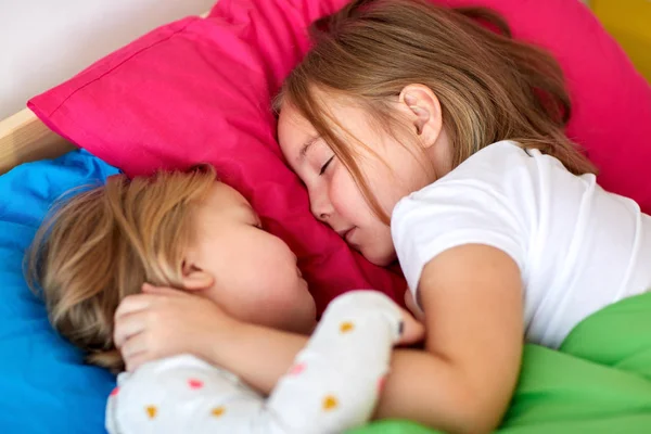 Счастливые маленькие девочки, спящие в постели дома — стоковое фото