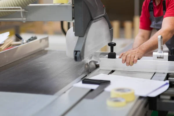 Carpenter with panel saw and fibreboard at factory — Stock Photo, Image