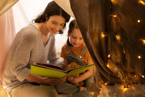 Libro de lectura familiar feliz en tienda de campaña para niños en casa —  Fotos de Stock