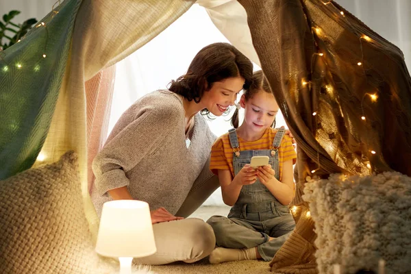 Lycklig familj med smartphone i barntält hemma — Stockfoto