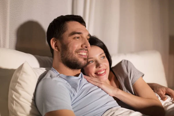 Feliz pareja viendo la televisión en la cama por la noche en casa —  Fotos de Stock